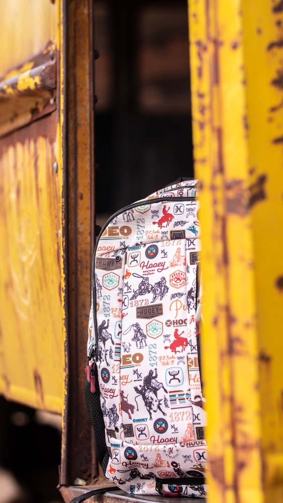 Styled photo of the Rockstar, Rodeo pattern back pack on an old, yellow, rusted out bus