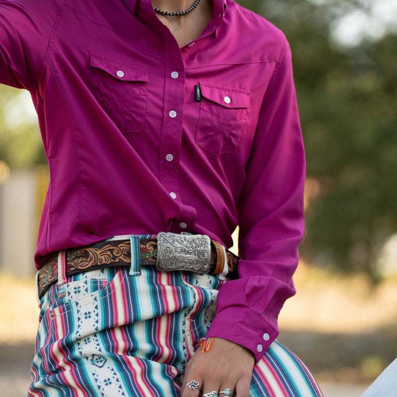 close up of purple sol shirt, tooled leather belt, and multi colored pants