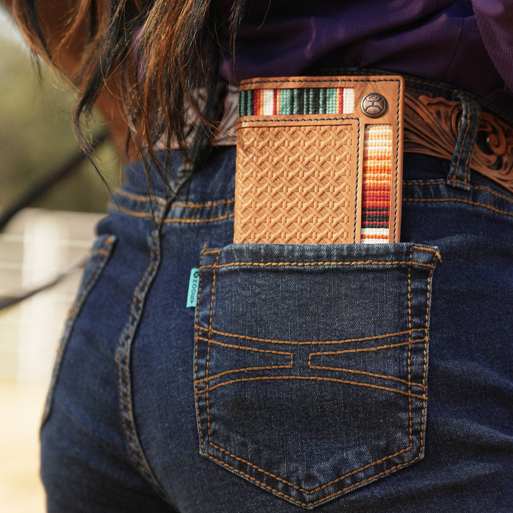 Tarlo basket weave tan and serape bi-fold wallet in the back pocket of Hooey dark wash jeans
