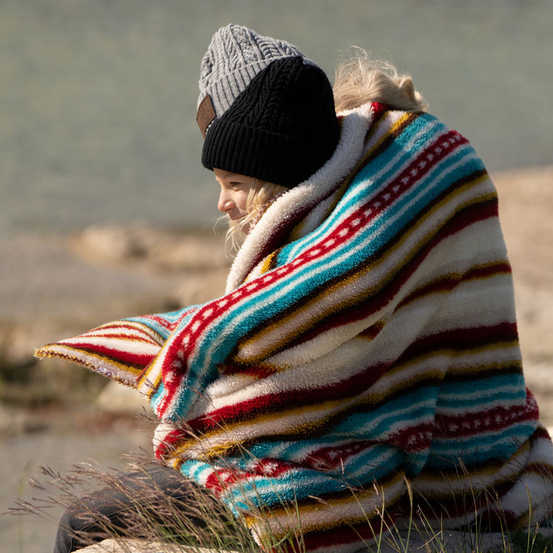 Young girl wrapped in Hooey fleece serape blanket in outdoor setting