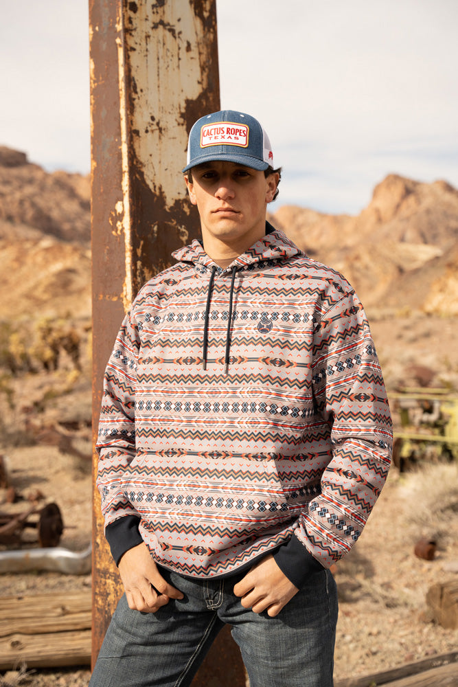 male model in denim Cactus ropes hat and jeans and Mesa navy, grey, blue, orange, black, white Aztec hoody in a mountainous setting
