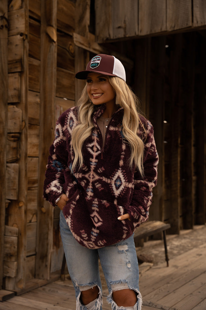 female model posing in ripped jeans, burgundy aztec pullover and burgundy hat
