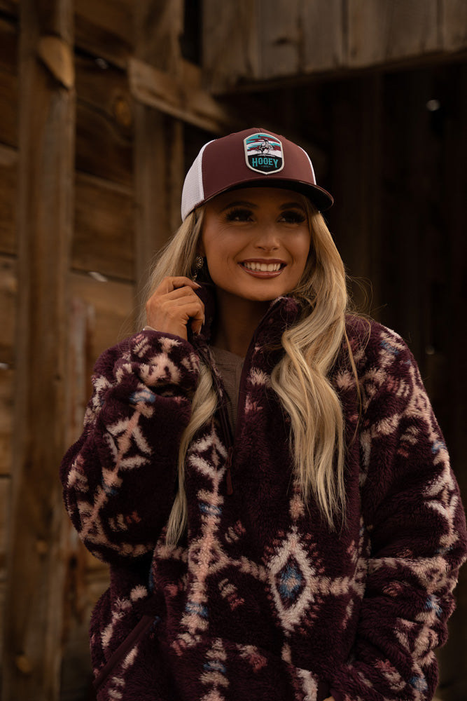 close up of blonde model wearing burgundy fleece pullover and burgundy and white hat