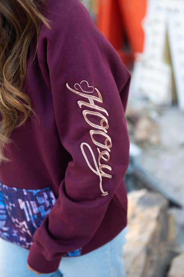 close up of logo on veracruz maroon hoody with purple and blue aztec pattern on pocket and hood