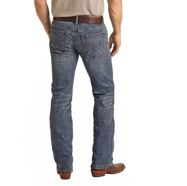 back view of the Medium Wash Hooey Revolver Slim Straight Jeans on male model wearing a tan tee, brown leather belt and matching cowboy boots