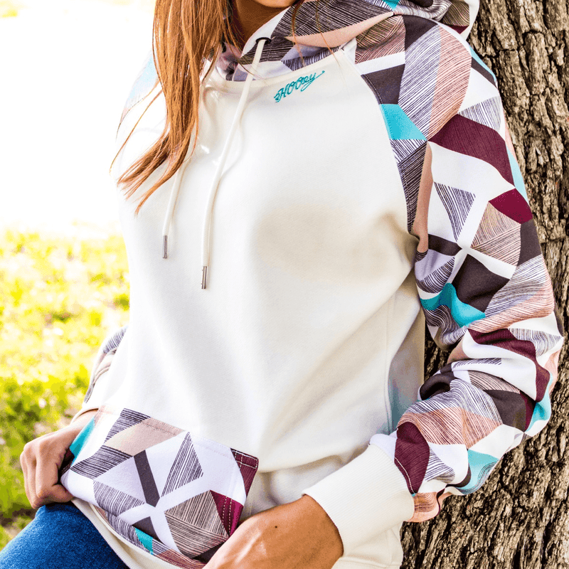 close up of the Morocco white hoody with tan, orange, blue, grey, purple patten on sleeves, pocket, and hood on female model