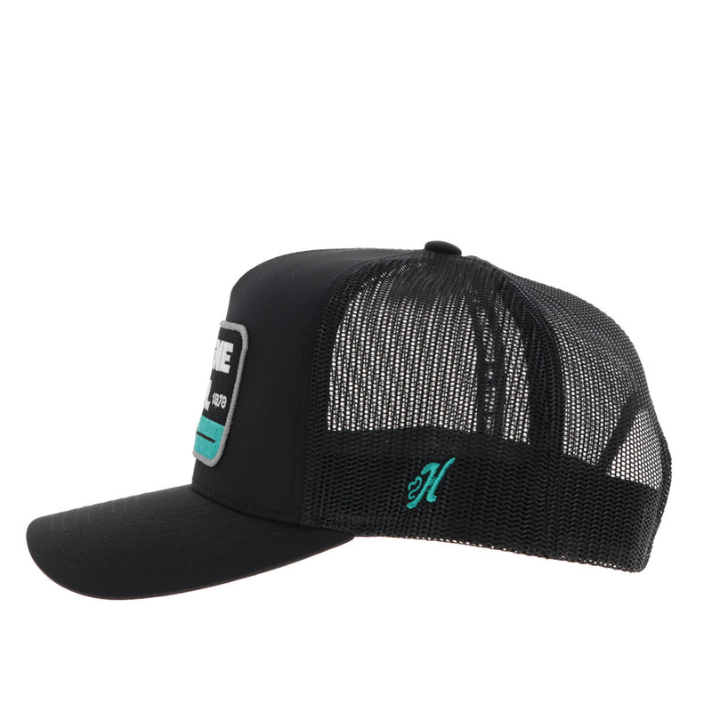left side of black on black Gruene Hall hat with teal H logo