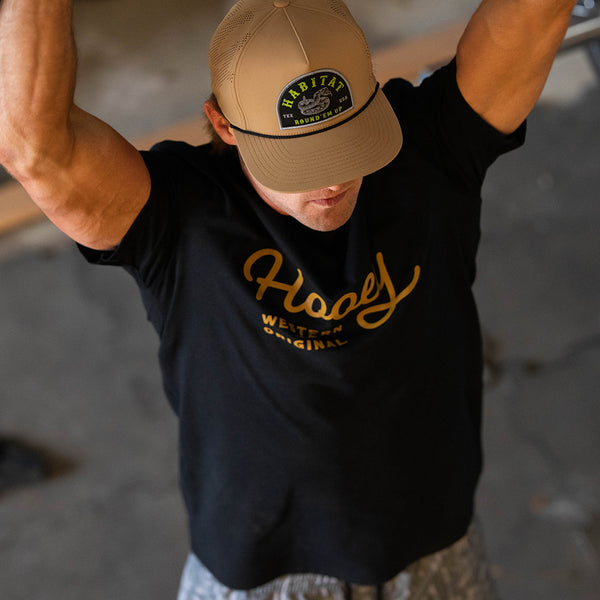 overhead image of the OG black tee with gold logo on a male model