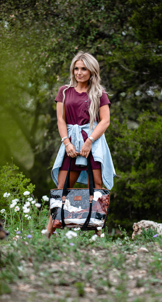 blonde female model posing with desert tote bag and maroon bamboo dress and blue sol shirt tied around waste