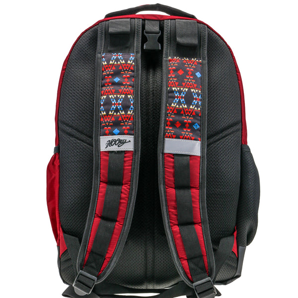 Back of the Ox backpack in burgundy with black back panel and red, blue, black, yellow Aztec pattern at top of straps, black Hooey logo, grey block at mid strap, and red and black detail ant the bottom of straps