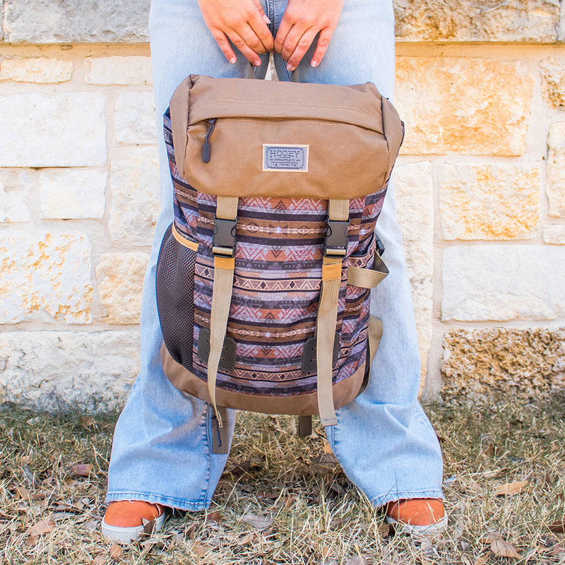 lifestyle image of model holding the Topper backpack in tan wit grey stripe pattern