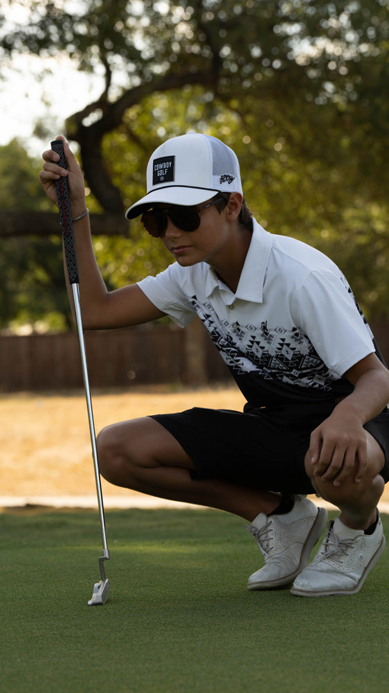 male model posing n black and white Aztec pattern golf polo with black and white golf hat