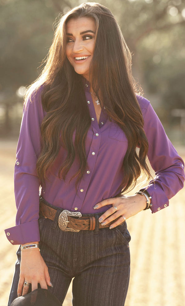 female model posing in Hooey trousers, tooled leather belt, and purple sol shirt