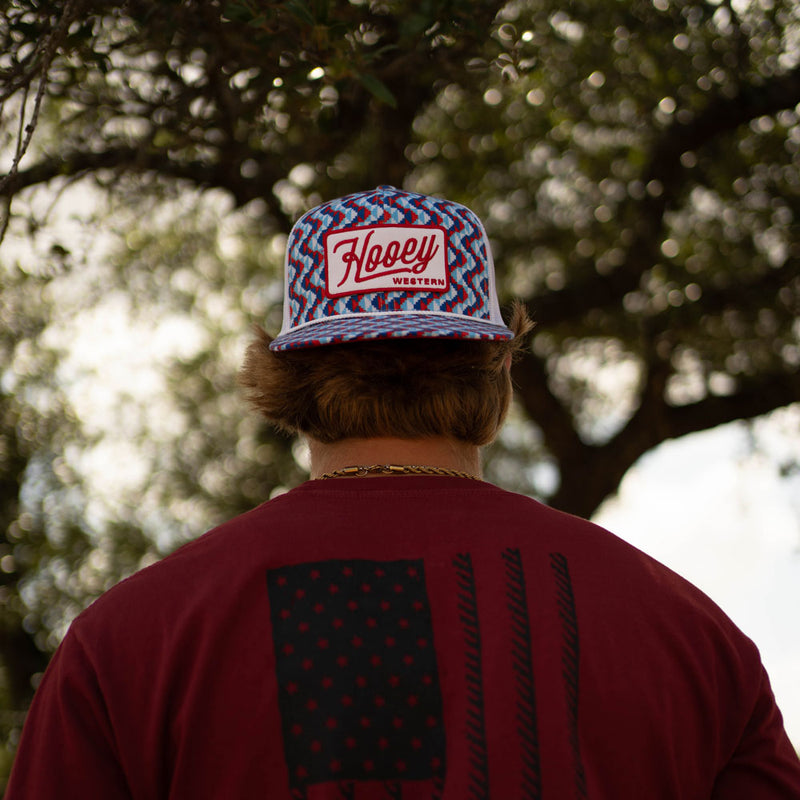 male model wearing liberty roper tee with red, white, blue hat