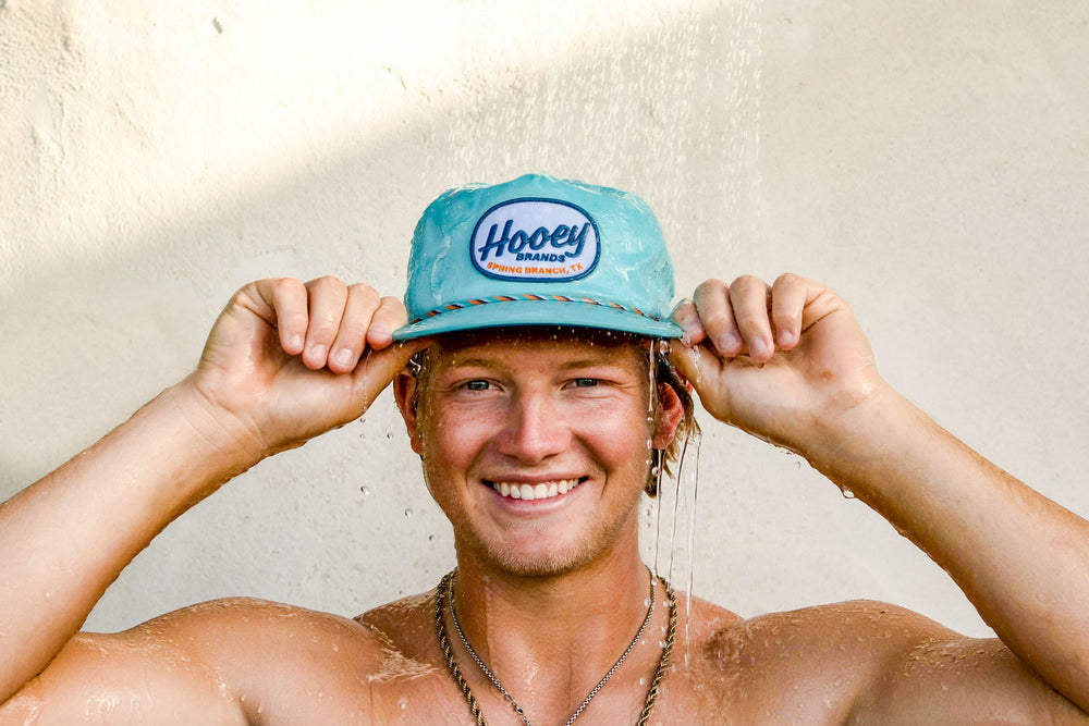 male model posing in team hooey hat under waterfall