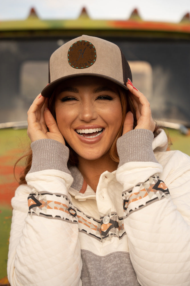 female model wearing heather grey and white quilted pullover with tan and brown Hooey hat