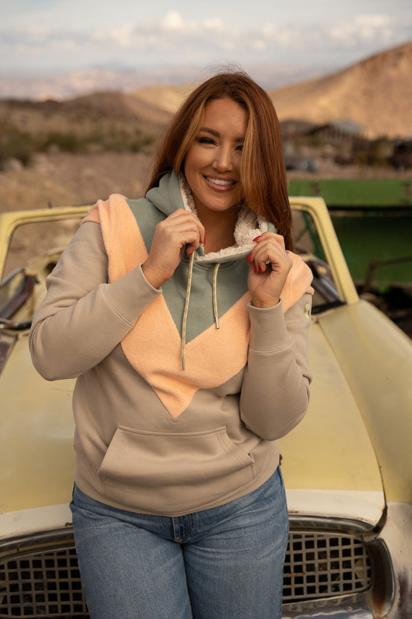 Lifestyle image of a model wearing the Berkley green, grey, and peach chevron hoody