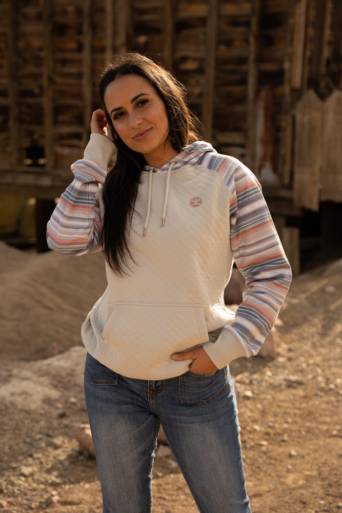 female model wearing the summit cream hoody with pink, grey, orange aztec pattern on pocket, sleeves, and hood