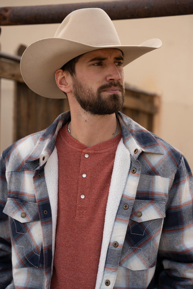 male model wearing grey plaid shacket, red henley, and tan cowboy hat