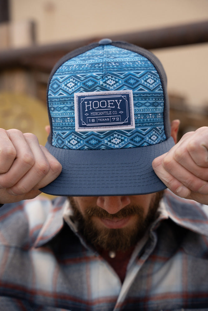 male model wearing navy and blue aztec hat with grey and white plaid shacket