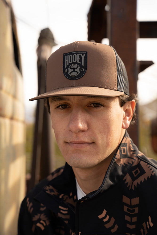 male model wearing black and brown aztec tech jacket with brown and black hooey hat
