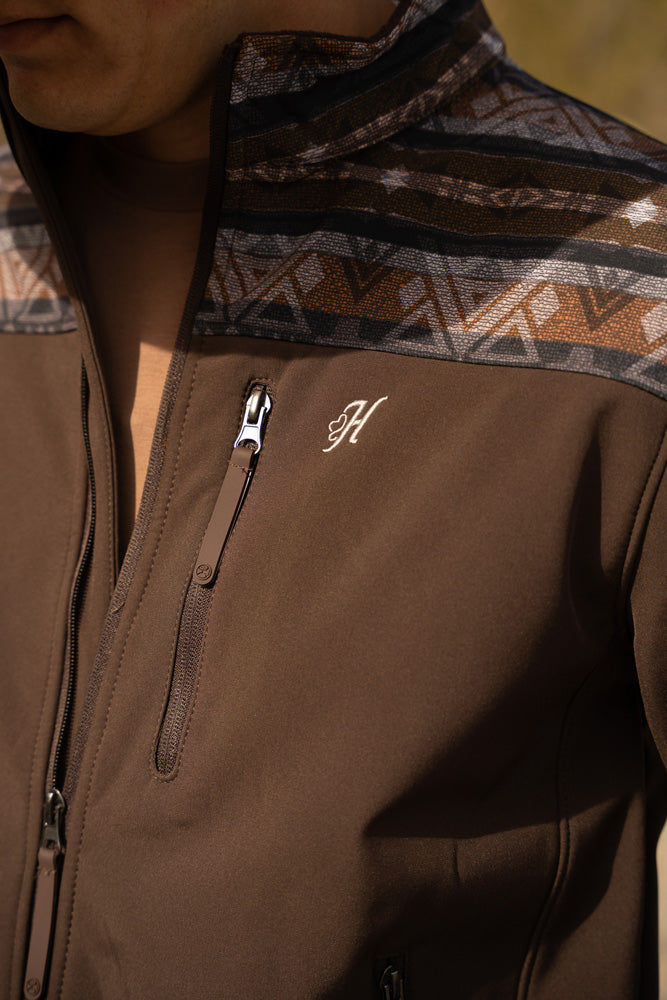 close up of H logo embroidered on brown zipper jacket