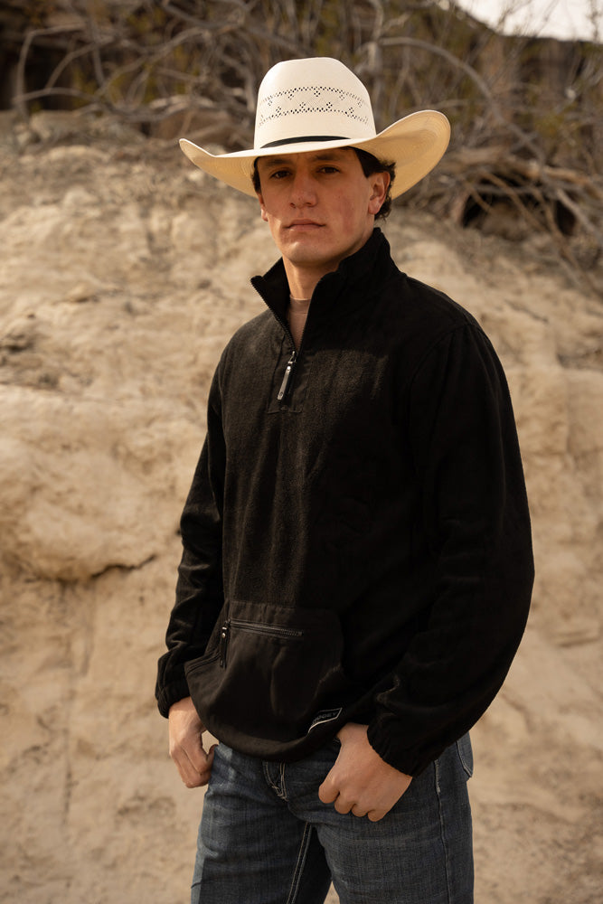 male model wearing a straw cowboy hat and the Hooey Fleece pullover in black in an desert setting