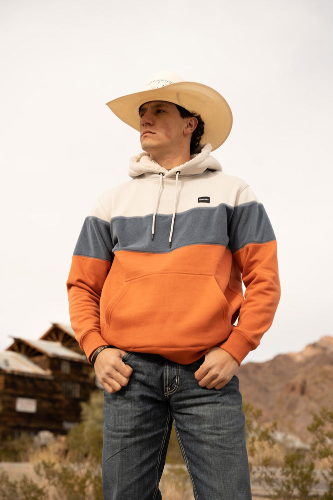 Lifestyle image of a model wearing the Breck orange, grey, and blue hoody