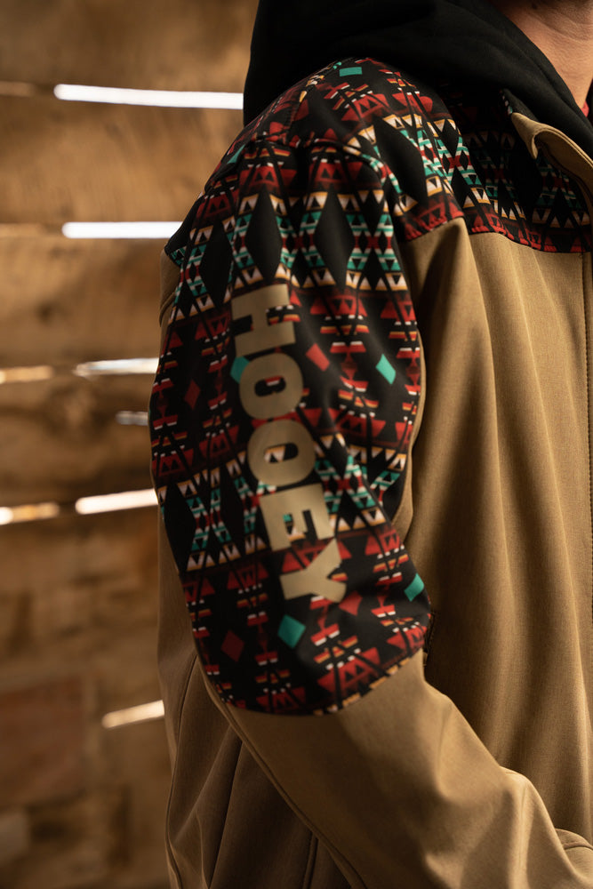 close up of Hooey logo on tan jacket with black and multi colored Aztec pattern shoulder pads and collar