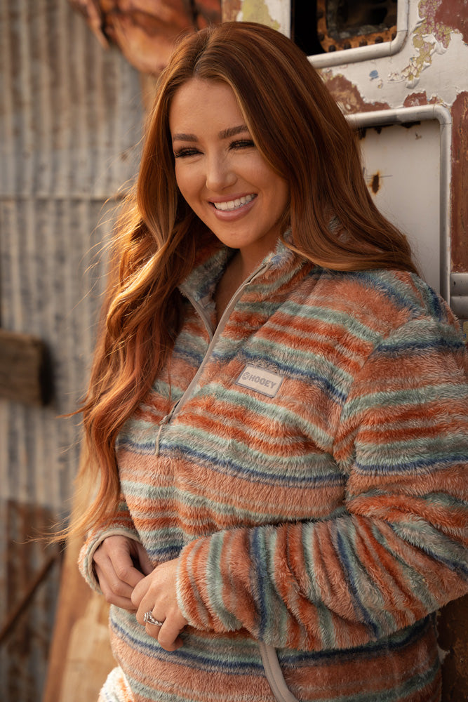 close up image of female model sporting multi colored Hooey, fleece pullover in rustic setting