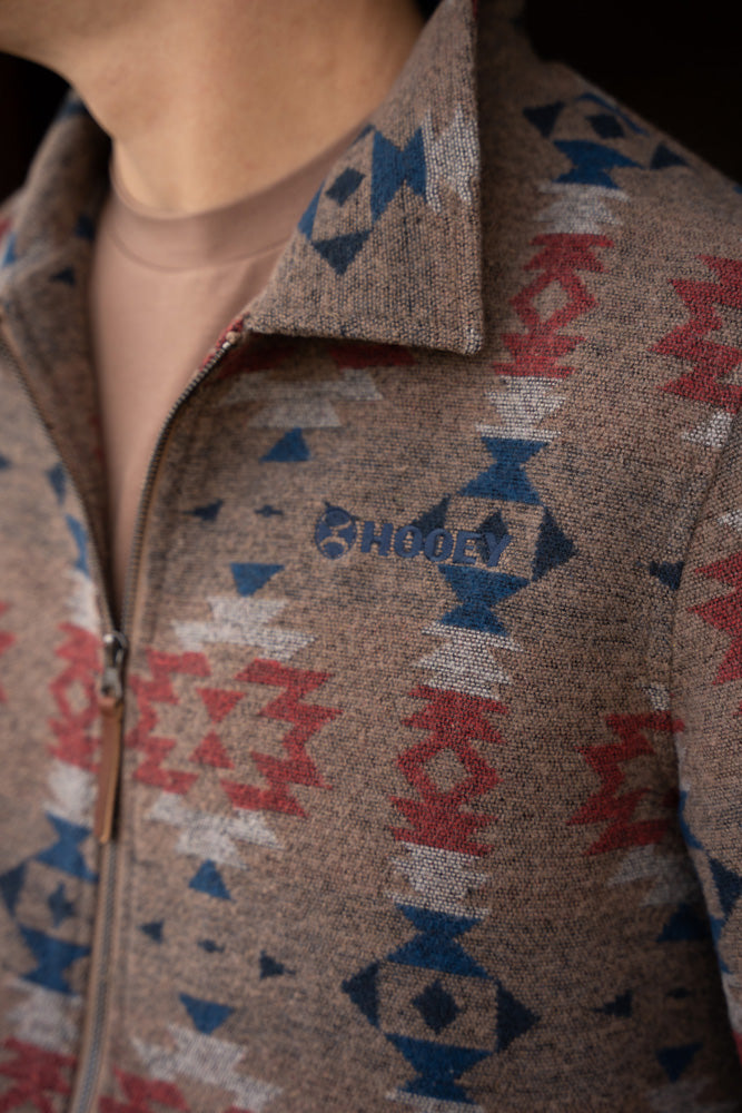 close up of brown zipper jacket with blue, red, and white Aztec pattern