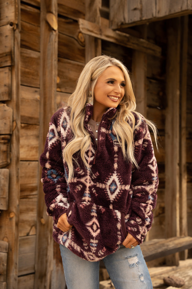 blonde female model wearing acid wash ripped jeans and maroon fleece pullover with aztec pattern