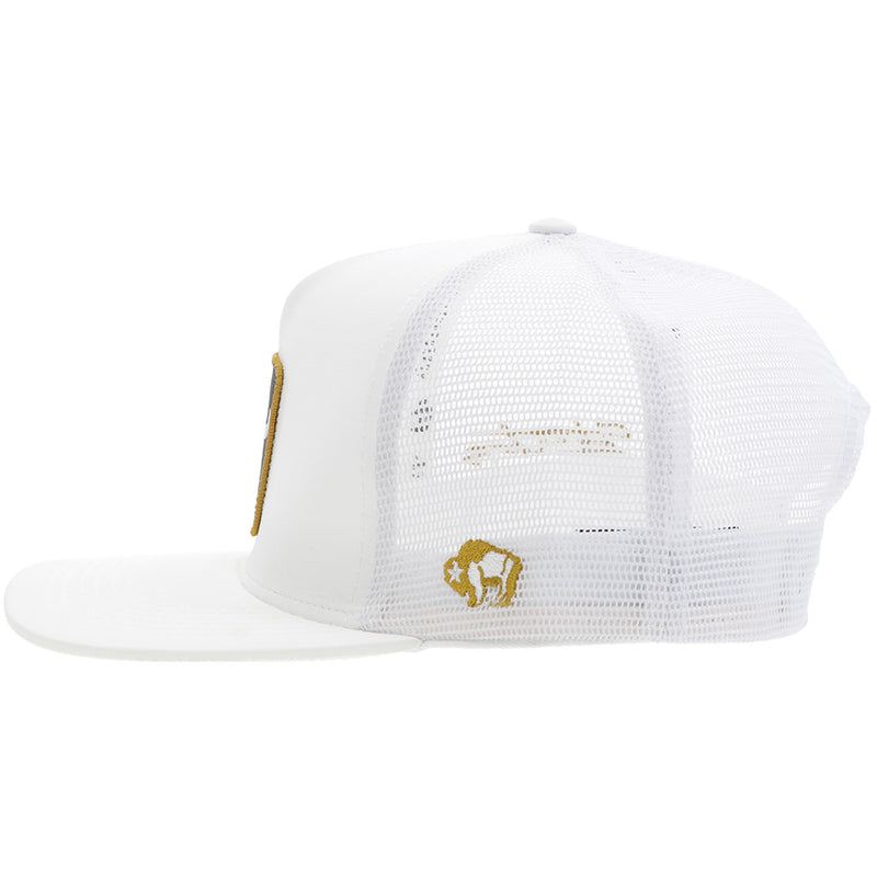 left side of Dusty Tuckness all white hat with black and gold logo patch, and gold buffalo embroidery