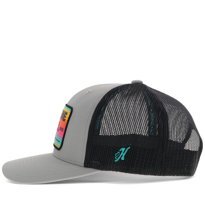 left side of black and grey Gruene Hall hat with pink, yellow, teal serape patch and teal H logo