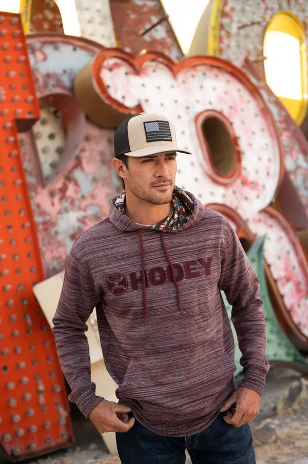 male model sporting the heather burgundy hoody posed in front of old signs