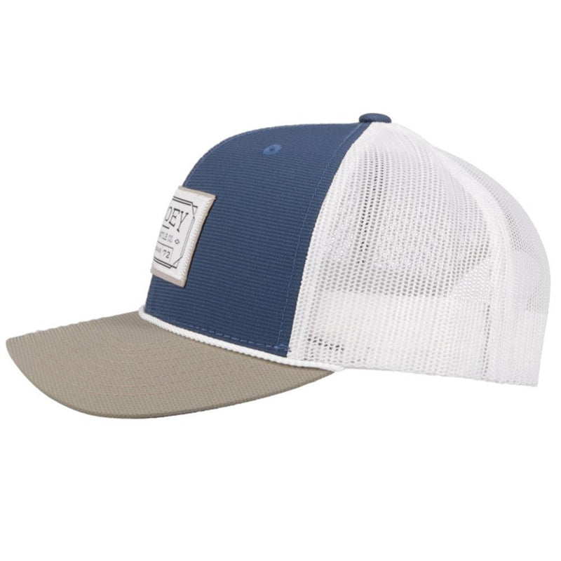 left side of the blue, white, and tan snapback hat with white patch and rope