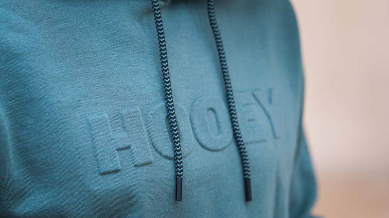 close up of the logo on the green ridge hoody with multi colored aztec pattern in the hood lining
