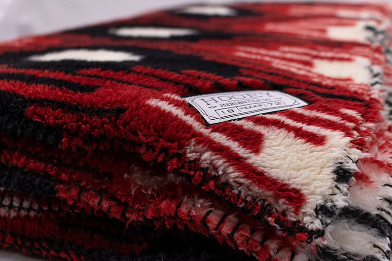 Close up of the logo patch on the red, black, and white saddle pattern blanket