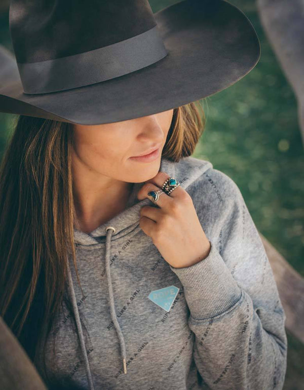 lifestyle image a brunet female model with a black felt cowboy hat wearing the Rope Like A Girl grey hoody