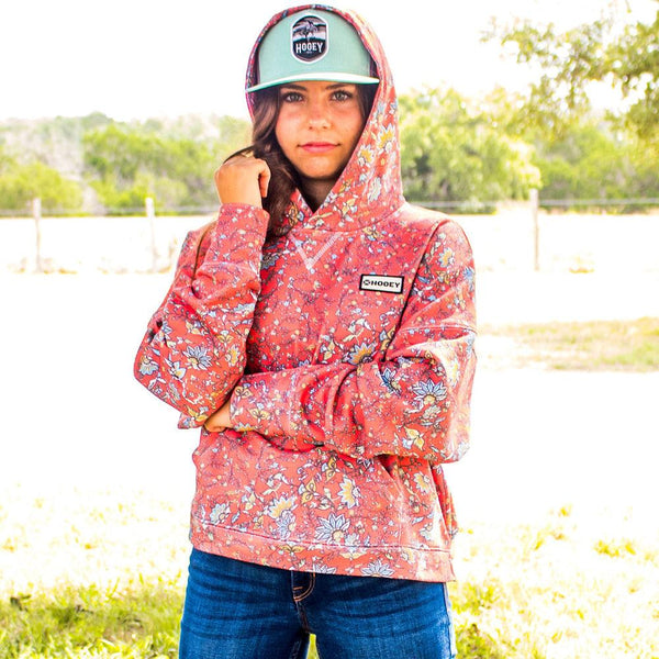poppy pattern hoody modeld by female model in jeans and teal Cheyenne hat in outdoor setting